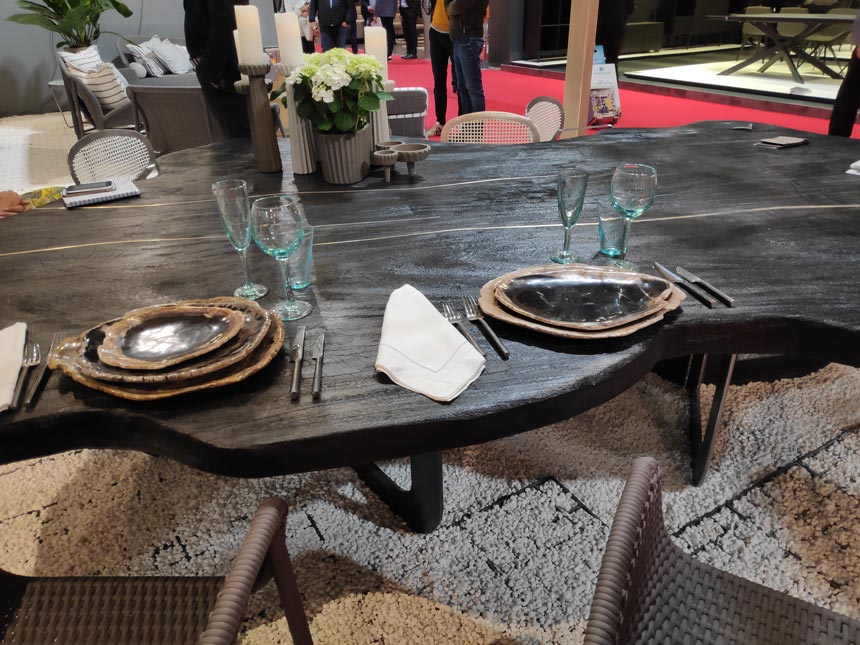 Detail of a dining setting with a dark stained vintage looking dining table from Mary& booth at iSaloni Milan.