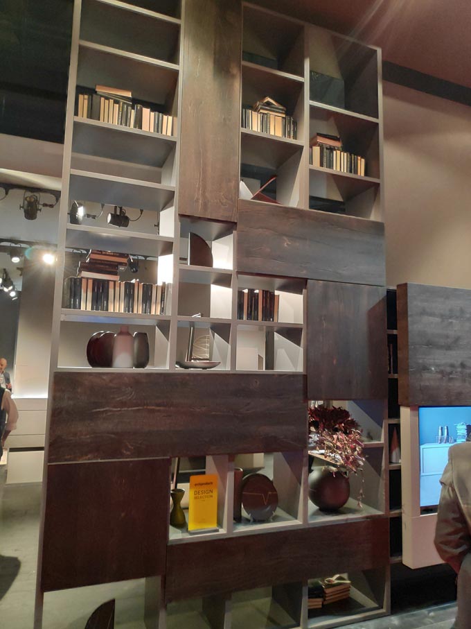 A tall bookcase with dark stained wood panels from Fimar at iSaloni2019 in Milan.