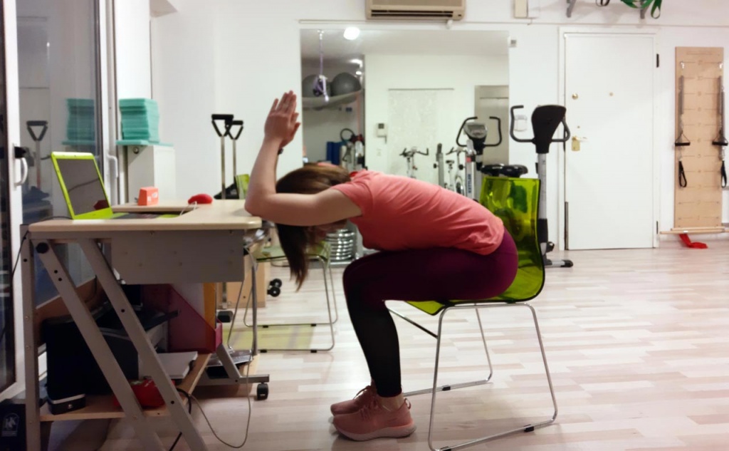 Ifiyenia Koskina while doing a stretching exercise by an office desk.