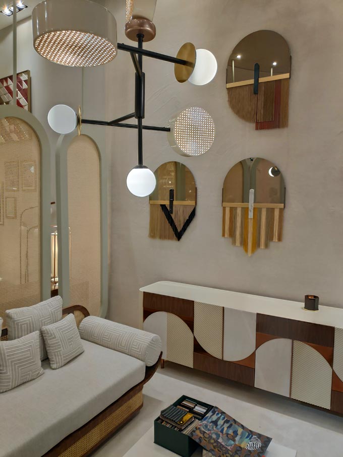 An off white sofa with an eclectic sideboard paired with a brassy modern chandelier and wall hangings from iSaloni 2019 in Milan.
