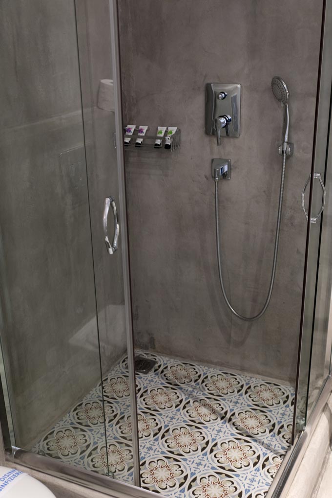 I love the combination of microcement walls in a shower with old cement tiled pattern flooring. Image by Antonis Drakakis.