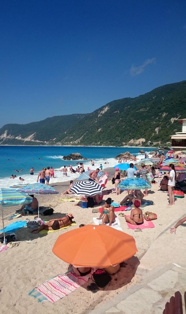 View of the the packed by people Agios Nikitas beach in Lefkada.