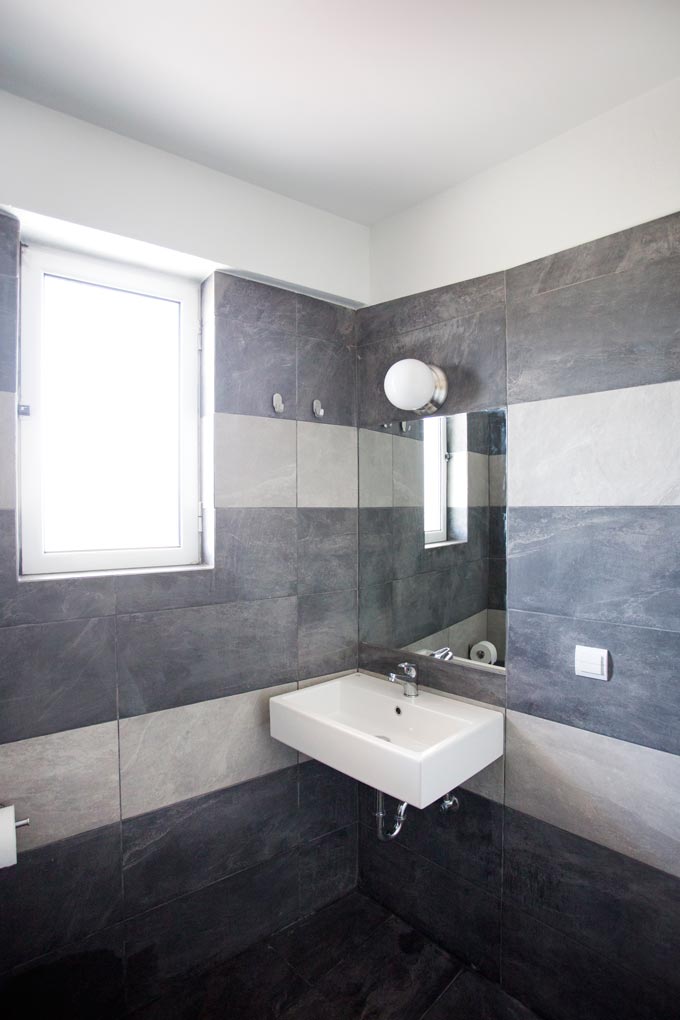 View of a contemporary minimal bathroom with grey wall tiling from a renovation project designed by Velvet Karatzas.