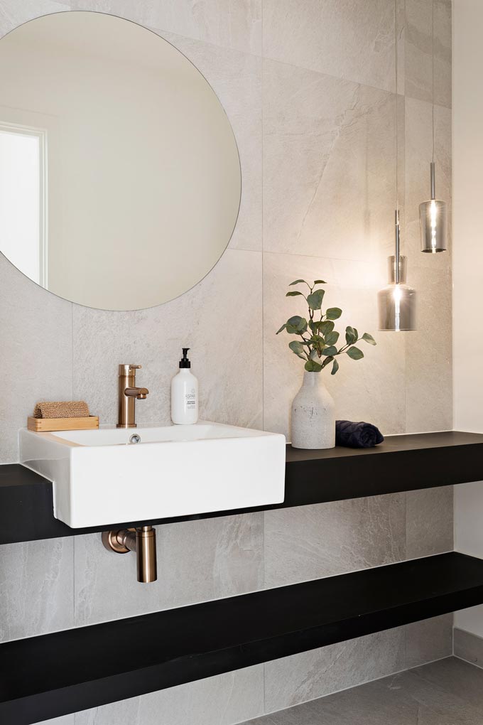 A stylish washbasin vanity with a round mirror over it. Image via Meir Australia Pty Ltd.