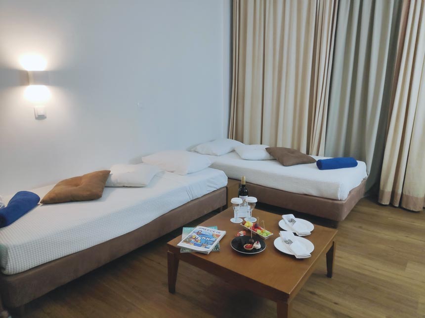 Partial view of the second bedroom with two single beds and a coffee table at a Grecotel Lux Me Rhodos apartment.