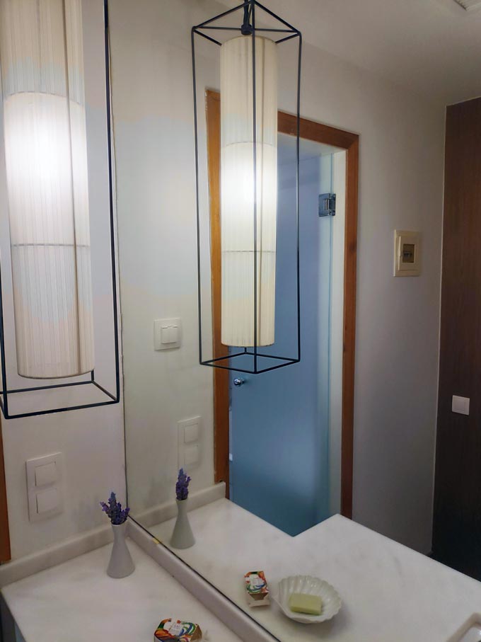 Partial view of a marble sink with a Japandi styled pendant light.