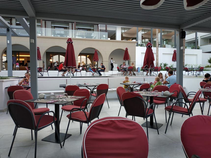 The black steel furniture with the deep red cushioning of the outdoor dining space at Grecotel Lux Me Rhodos.