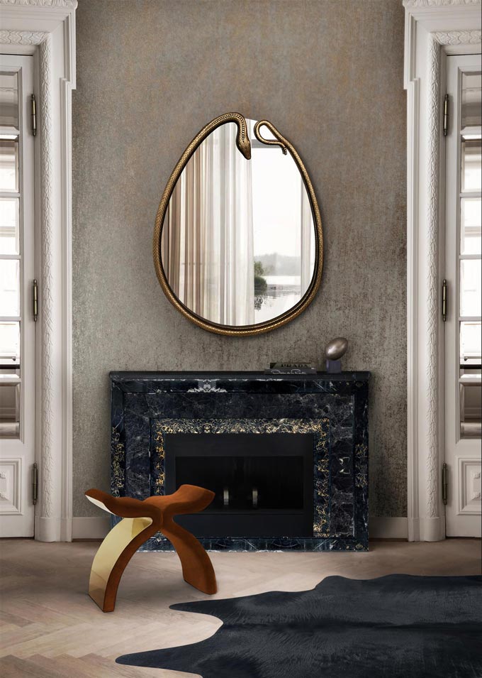 An egg shaped mirror over a black fireplace looking amazing. Image by KOKET.