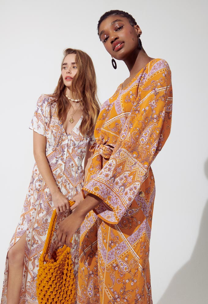 Print and pattern fashion: Two women in two orange hue print pattern summer dresses that have a bit of a boho flair to them. Image by Miss Selfridge.