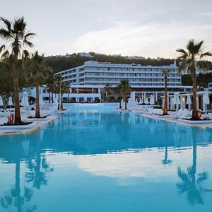 View of the main pool and central building of Grecotel Lux Me Rhodos after sunset hours.