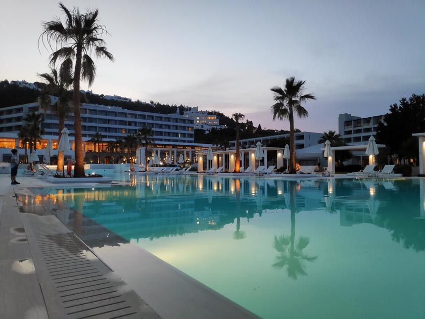 View of the main pool and central building of Grecotel Lux Me Rhodos after sunset hours.