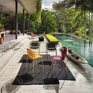 Cielo and circo chairs by an infinity pool somewhere that looks very exotic and tropical.