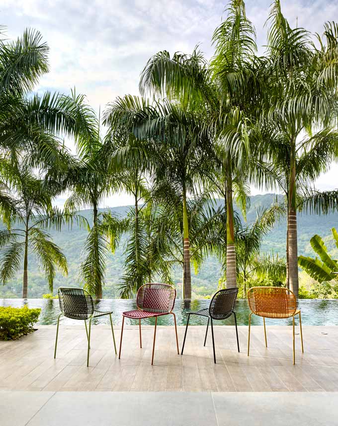 Cielo chairs in front of an infinity pool and palm trees in the background.