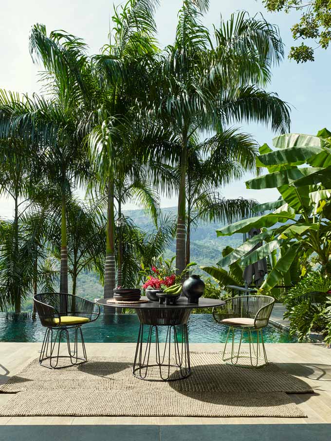 An exotic ames outdoor dining set with an infinity pool and tall palm trees.