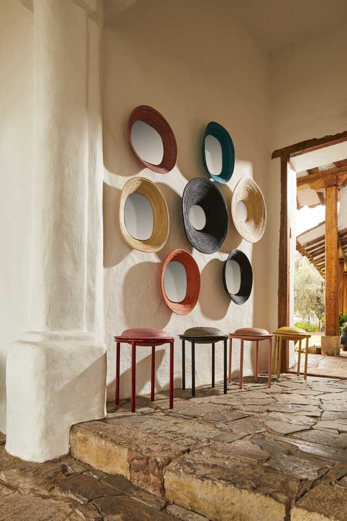 A gallery wall from killa mirrors making a statement and four cana stools underneath them at an entryway.