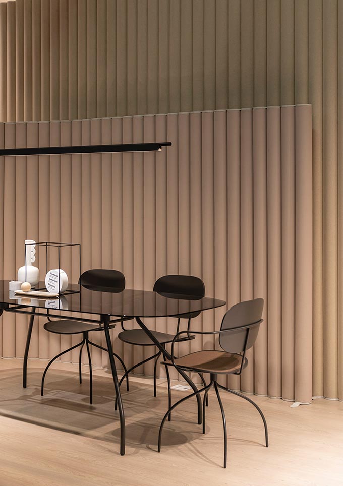 A minimal contemporary dining space with a muted terracotta accent wall made of tubular vertical forms in alignment.