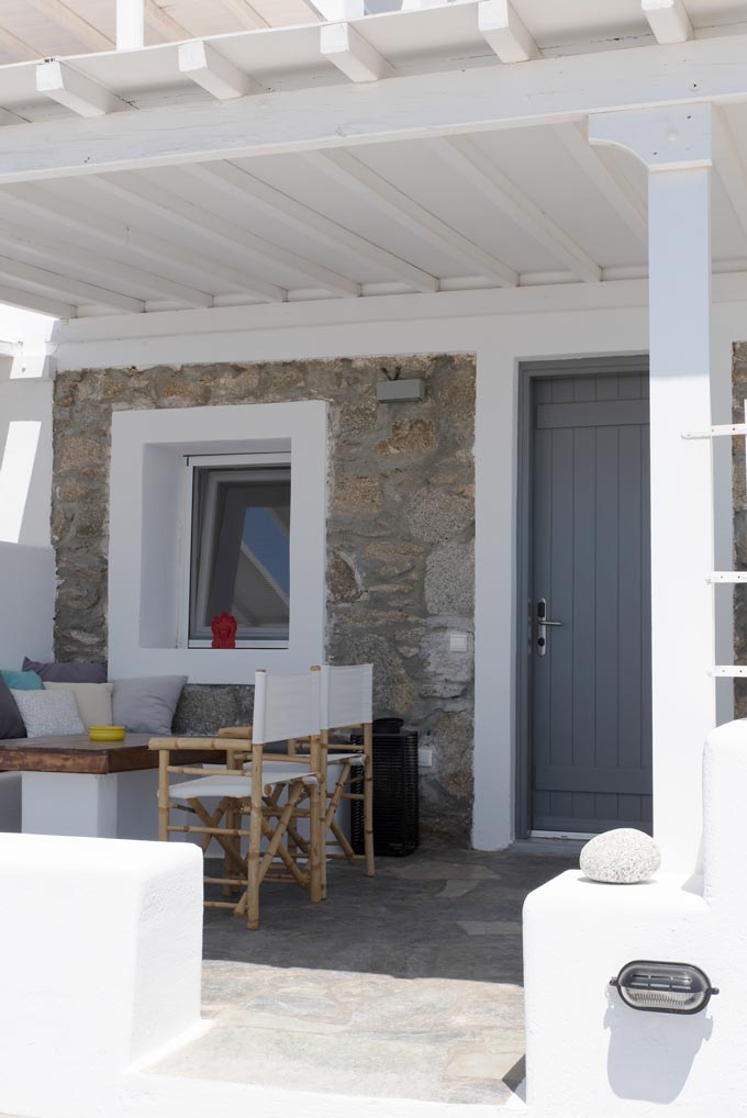 Looking at the exterior of a Cycladic minimal facade and terrace at Bellou Suites in Mykonos.