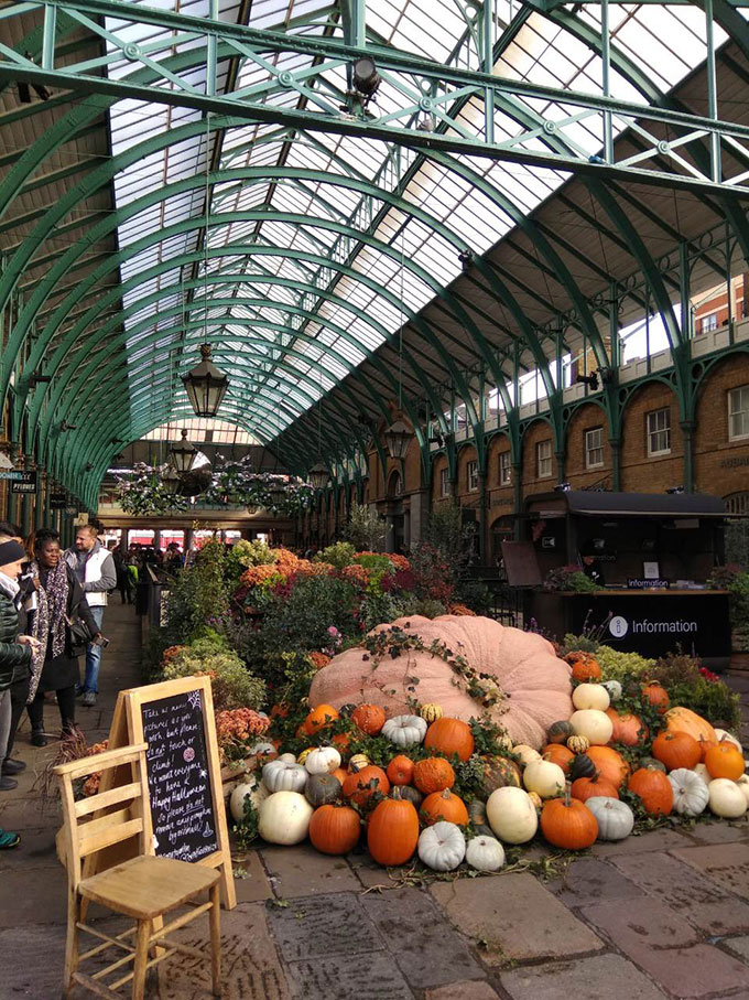 A huge pile of pumpkins used as Halloween decor at the entrance to the Food Market Hall at Covent Garden London.