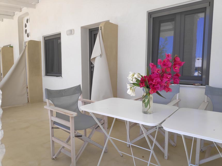 Cycladic minimal style: Partial view of the external facade of a room from Hotel Emily in Syros, with microcement flooring and a dining set for the guests to enjoy.