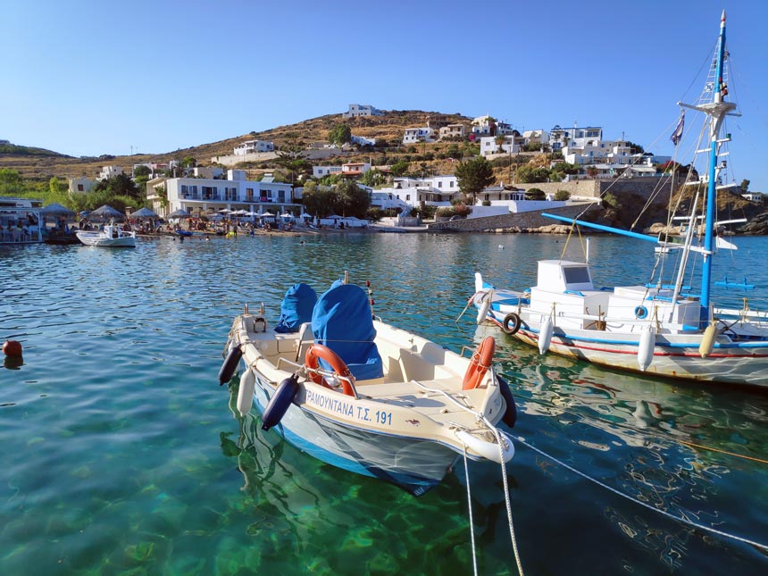 View of Hotel Emily in Syros from afar with the sparkling blue green waters and fishing boats in the foreground.