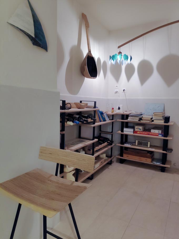 Cycladic minimal style: Racks of shelves with table games, wine bottles and decor at the reception lobby of Hotel Emily.