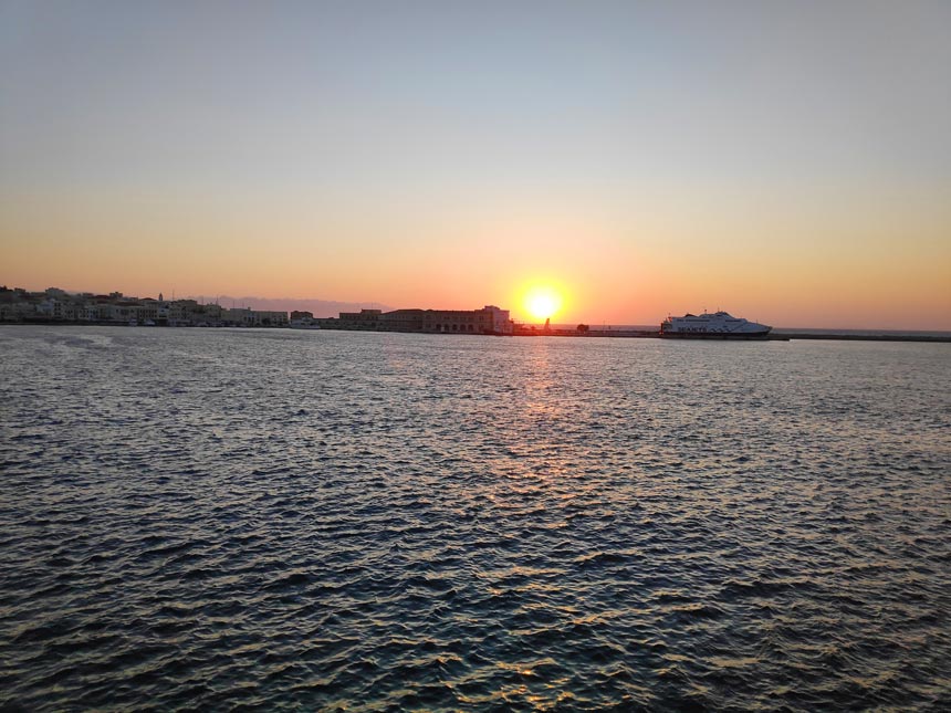 The sun rising behind the dock of Hermoupolis port in Syros.