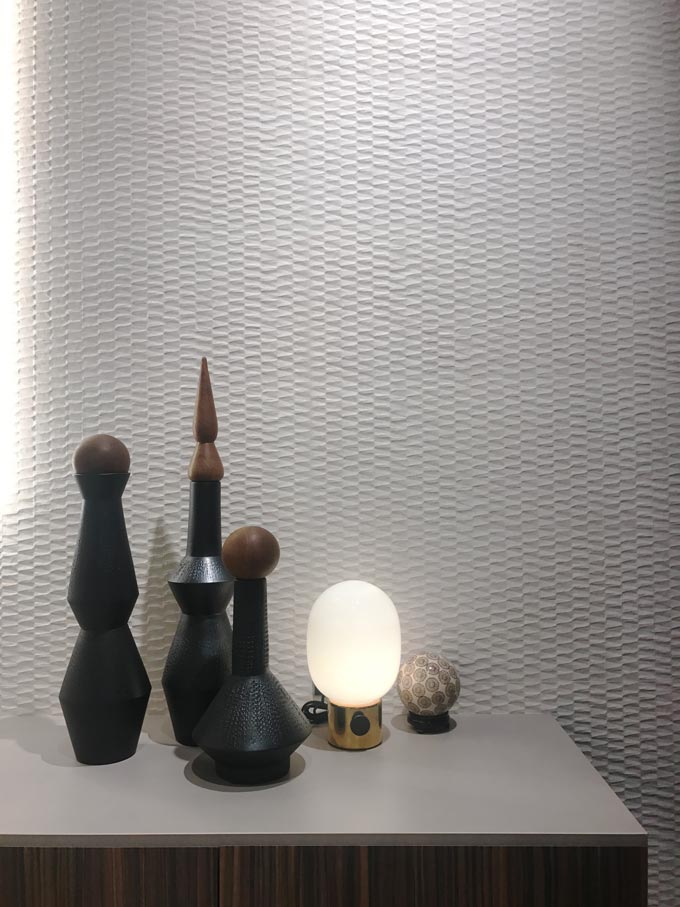 A white 3d effect tile acts like an accent wall behind some black decor. Tile from FAP an Italian company.