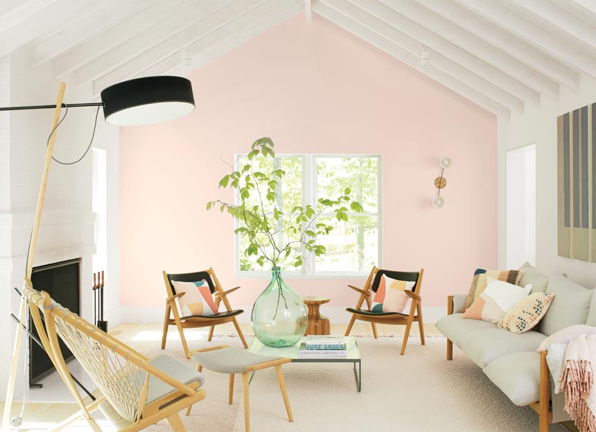 A contemporary and very brights living room with a soft pink wall in the background known as First Light from Benjamin Moore. Image via Benjamin Moore.