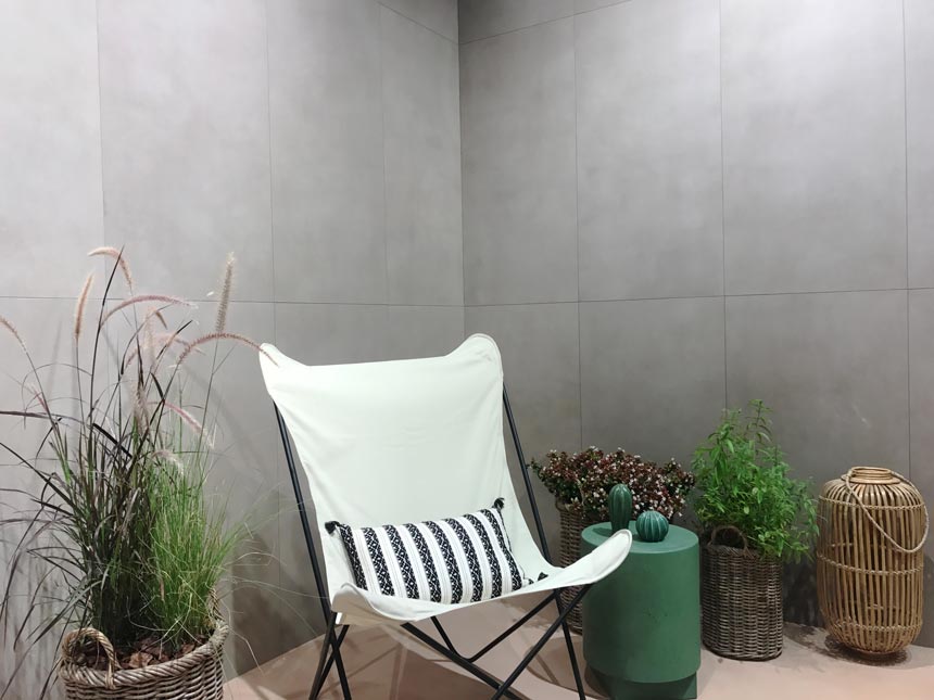 A vignette setup as if outdoors with stone looking tiled walls at an installation at Cersaie 2019. Stand of Marca Corona.