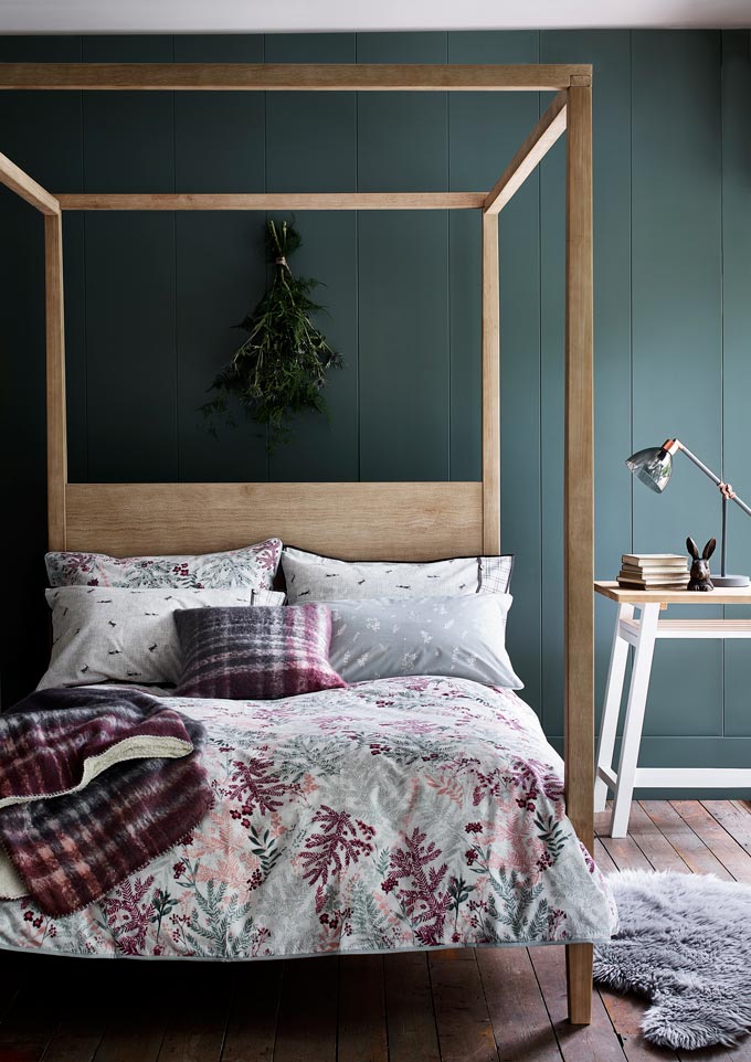 What a cozy and inviting bedroom with a rustic bed and a green accent wall. Image via Argos.