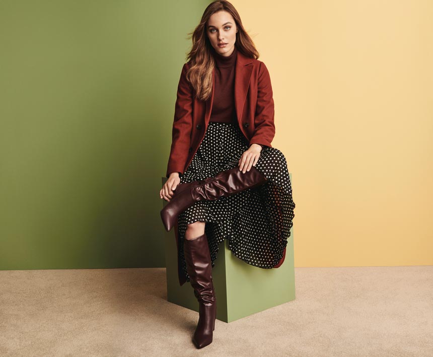 Winter outfits lookbook: A stylish outfit with a burnt orange top, a polka dot pleat skirt, knee high boots and jacket. Image via Dorothy Perkins.