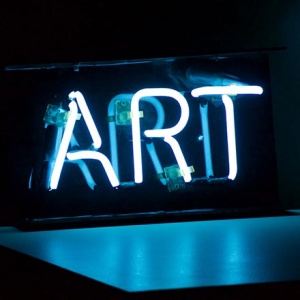 A neon sign that reads 'ART' against a black background
