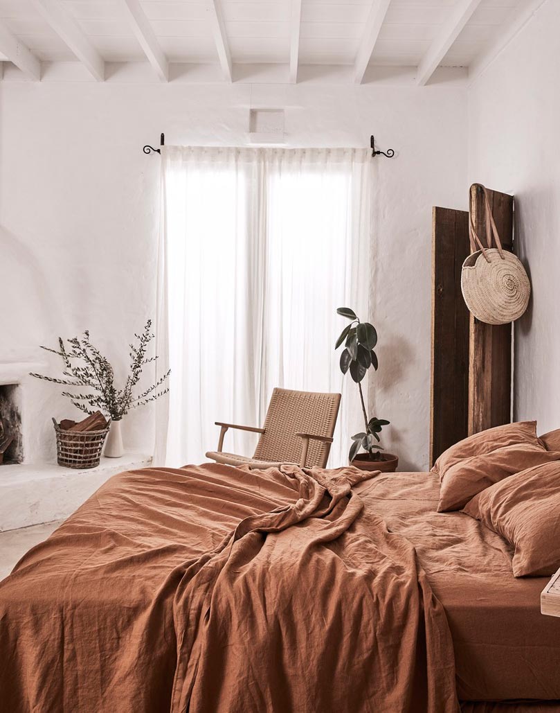 A bright Scandi-boho chic bedroom with rusty hue bedding, looking out of this world. Image via IN BED. Photo by Terence Chin Photography.