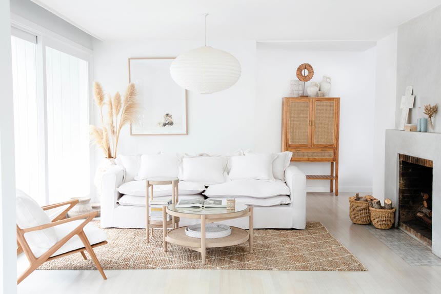 A bright white Scandi boho living room with a neutral color palette and elements like cane and rattan. Image via OZ Design Furniture.