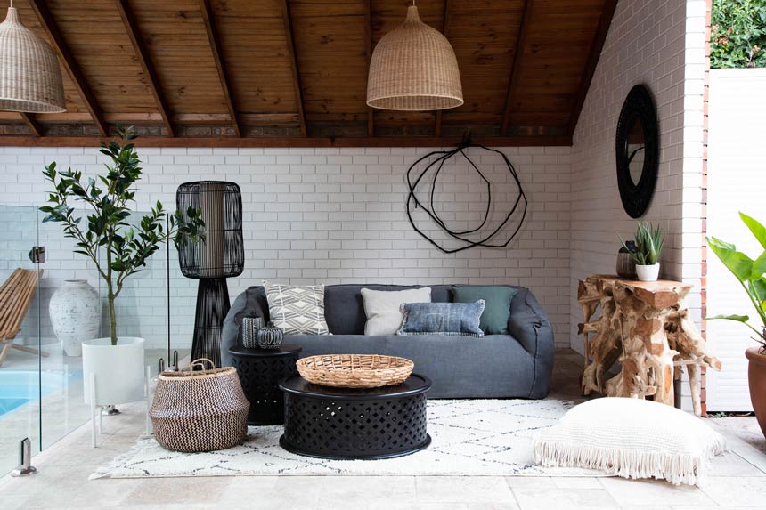 An elegant Scandi-boho setup with a blue sofa and a rattan pendant light hanging from a wooden sloped roof. Image via OZ Design Furniture.