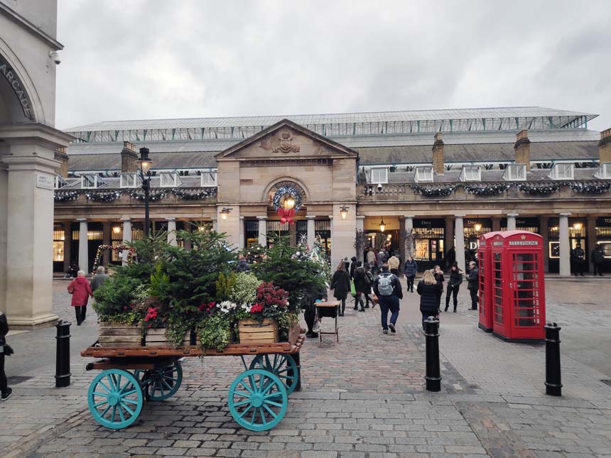 View of the walkway towards Covent Garden's Halls with Christmas decorations around and plenty of walking by people.