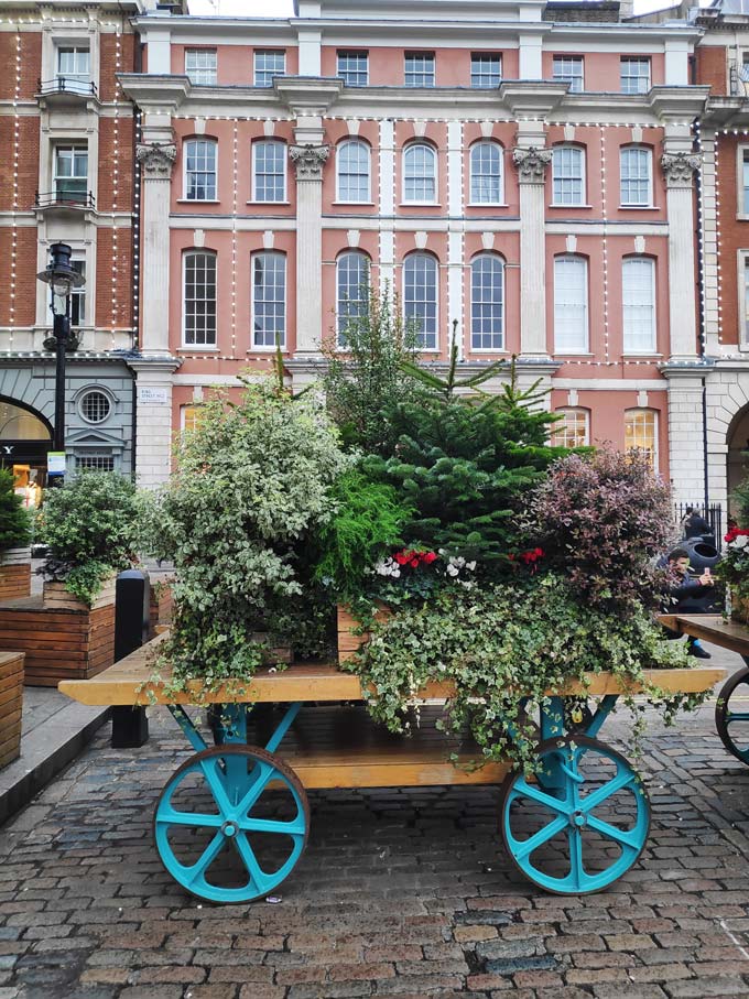 A wheel cart decorated with Christmas trees and plants at Covent Garden's square in London.