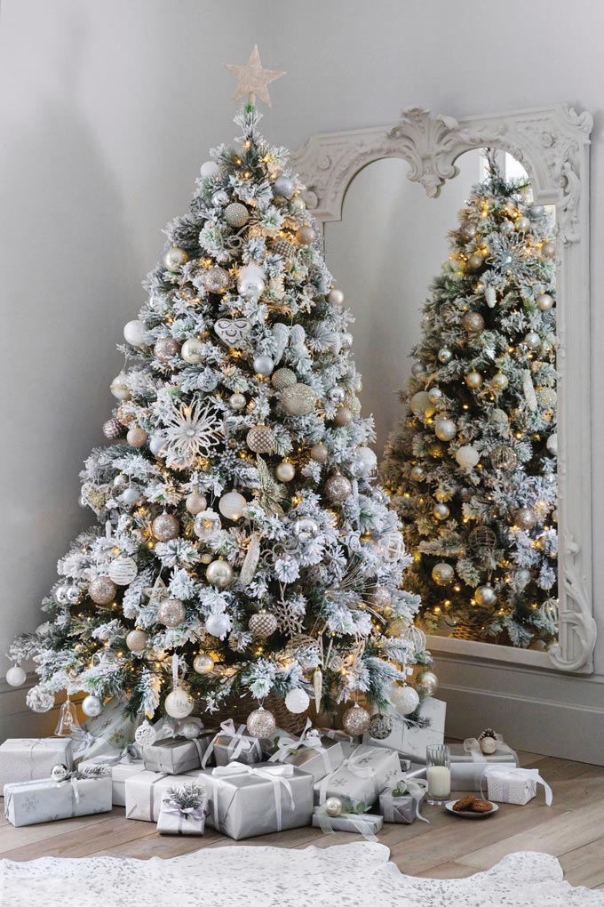 An almost white Christmas tree decorated with white and gold baubles. A real classic option. Image via Amara.