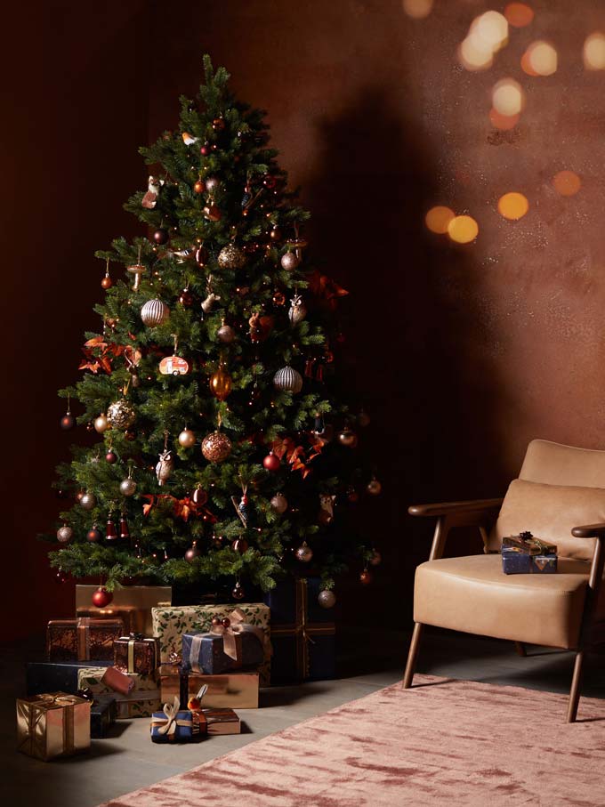 A green Christmas tree with deep rusty decorations - warm and inviting. Image via John Lewis & Partners.