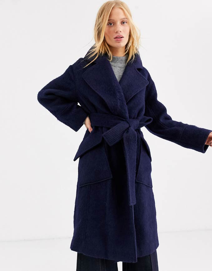 A blonde woman wearing a navy blue wool coat. Image via ASOS.