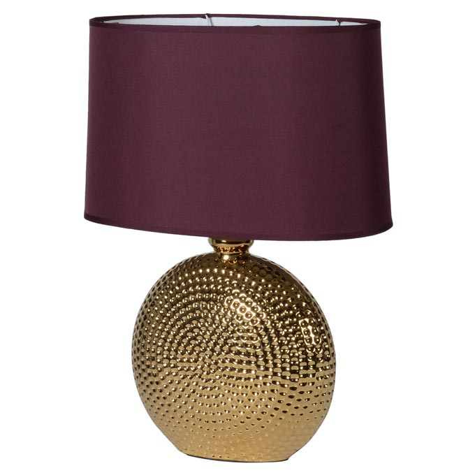 A hammered gold table lamp with a burgundy shade. By Audenza.