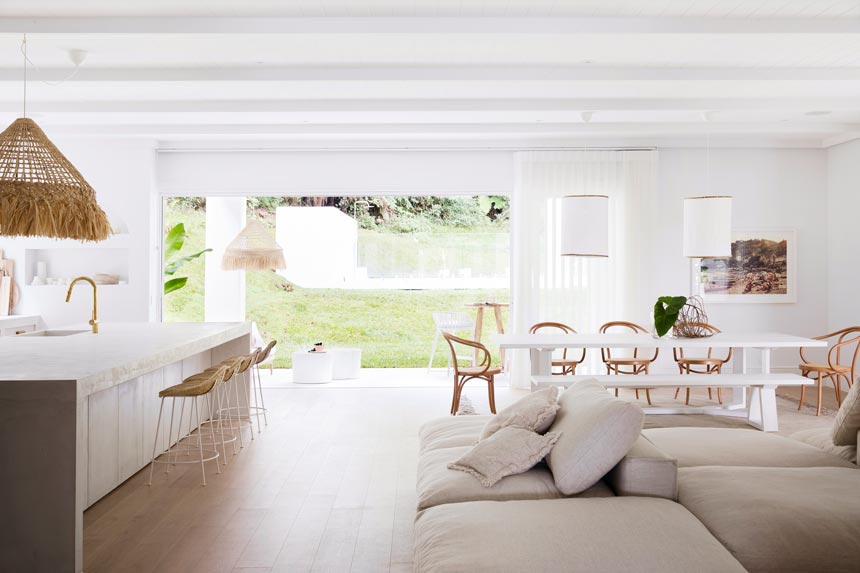 House Tour: Looking at the open plan space with a kitchen on the left and dining and seating on the right. It's white, bright, minimal and almost too stylish to bare. Photo: Three Birds Renovations/Raja Homewares.