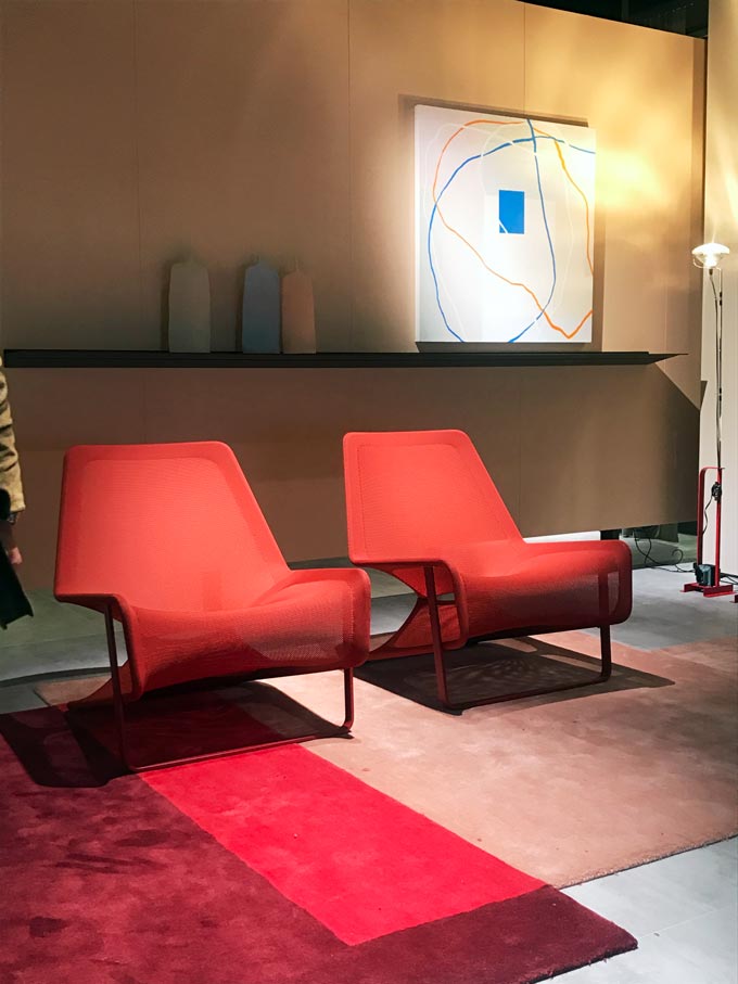 Two contemporary red armchairs side by side resting on a color blocked area rug.