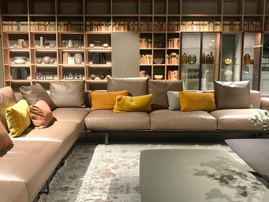 A living space installation with a large bookcase and two sectional leather sofas in a contemporary setting.