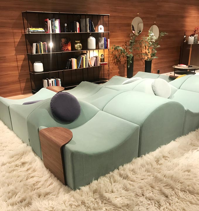 View of the Ligne Roset stand with a curvy light green modular sofa at the imm Cologne 2020.