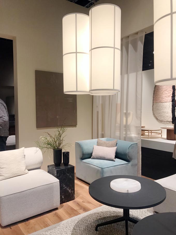 Big pendant lights hanging over a contemporary setting with an off white sofa and a light blue armchair.