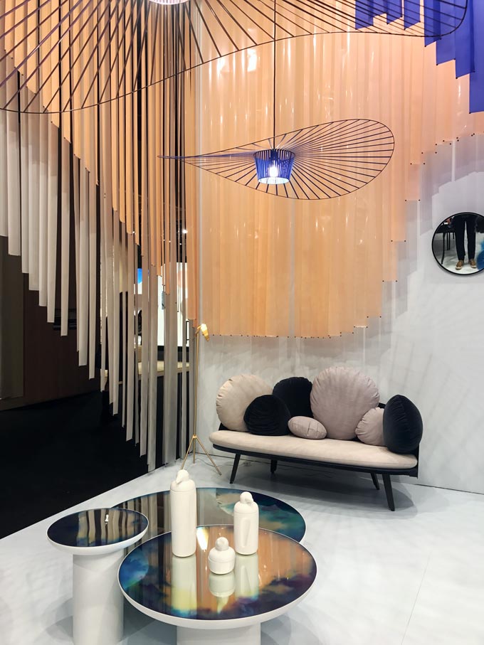 A funky installation with a curvy sofa and round coffee tables featuring a delightful pendant light at Petite Friture during the imm Cologne 2020.