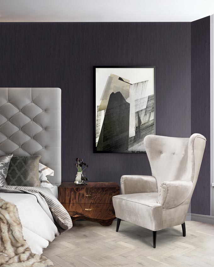 A beautifully crafted wooden bedside table - Huang by Brabbu featured against a dark moody mauve wall and a light grey bed and a grey armchair too. Image: Brabbu Design Forces.