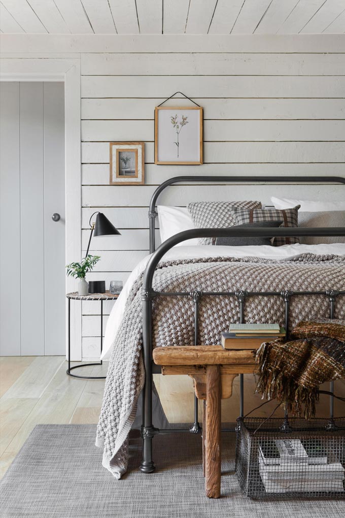 A Country chic styled bedroom with a round bedside table next to the steel frame bed. Image by Amara.