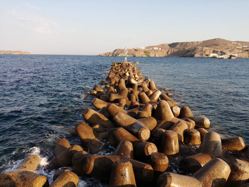 Wave breaking boulders aligned by the port of Hermoupolis, in Syros. A smartphone image.
